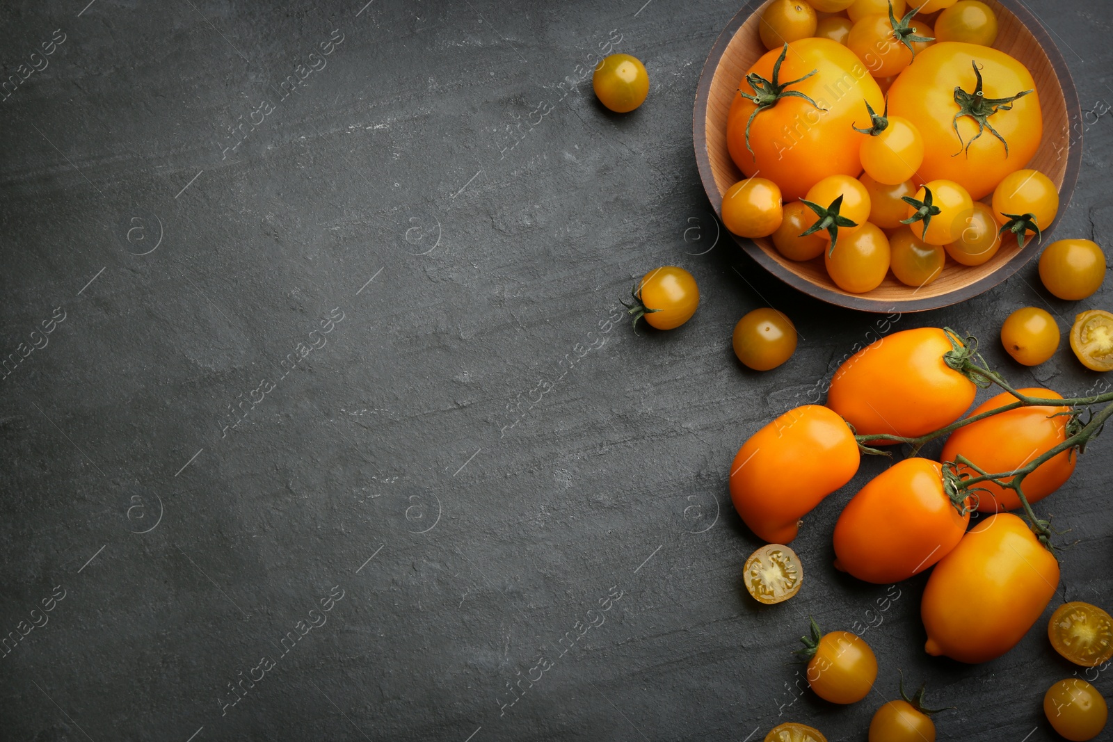 Photo of Ripe yellow tomatoes on black table, flat lay. Space for text