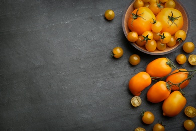 Photo of Ripe yellow tomatoes on black table, flat lay. Space for text