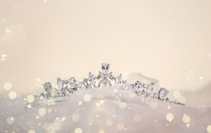 Image of Beautiful tiara with diamonds on cloth, space for text. Bokeh effect