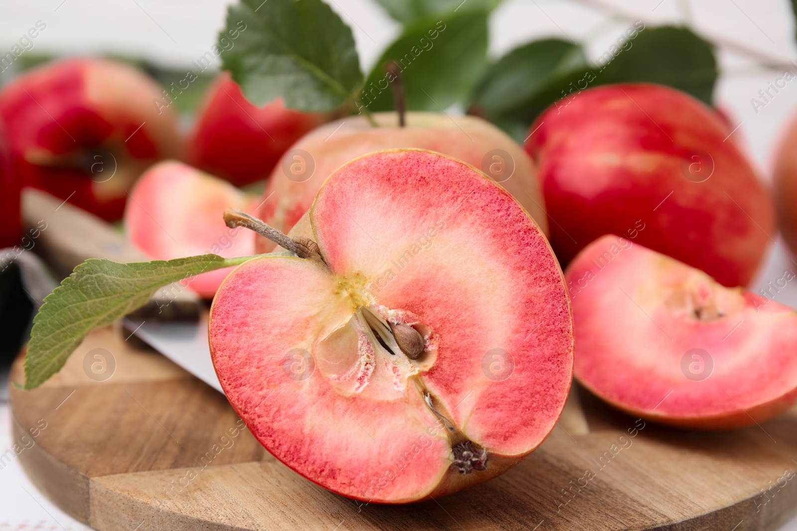 Photo of Tasty apples with red pulp on wooden board, closeup