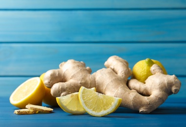 Photo of Fresh lemons and ginger on blue wooden table. Space for text