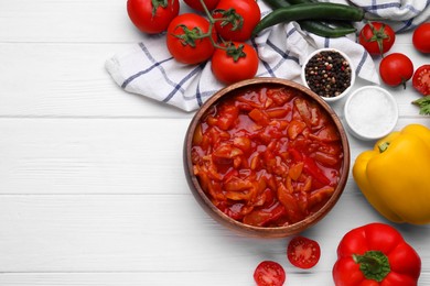 Delicious lecho in bowl and fresh ingredients on white wooden table, flat lay. Space for text