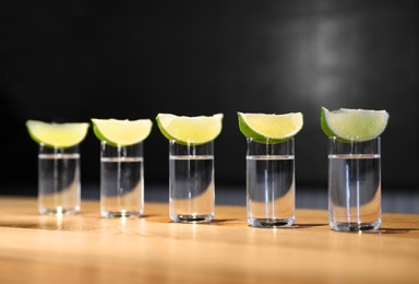 Vodka shots and lime slices on wooden bar counter