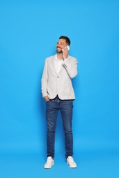 Handsome man talking on phone against light blue background