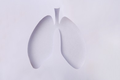 Photo of Paper with hole in shape of human lungs on white background, top view