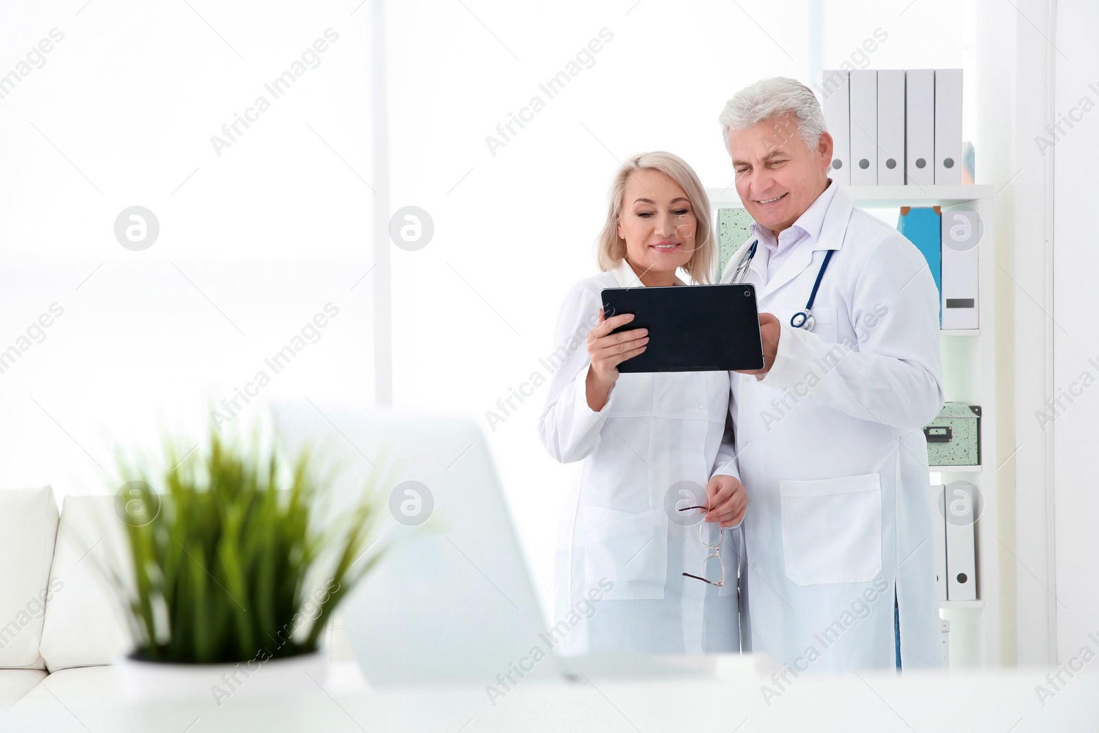 Photo of Mature female receptionist and senior male doctor working in hospital