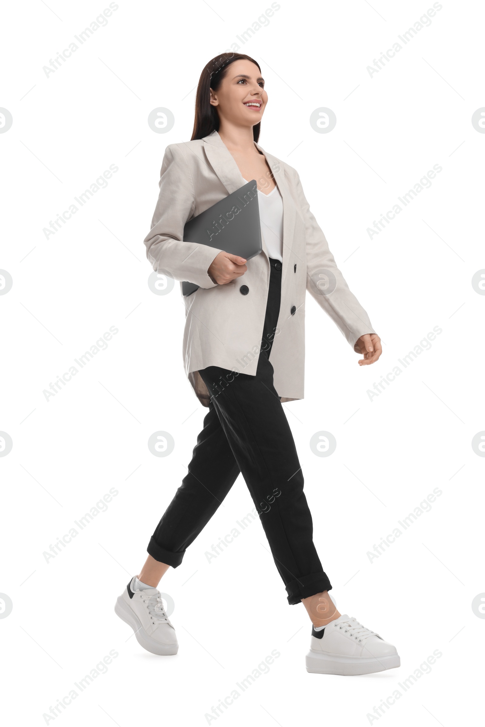 Photo of Beautiful businesswoman in suit with laptop walking on white background