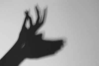 Shadow of hands like deer on light background, closeup with space for text. Black and white effect