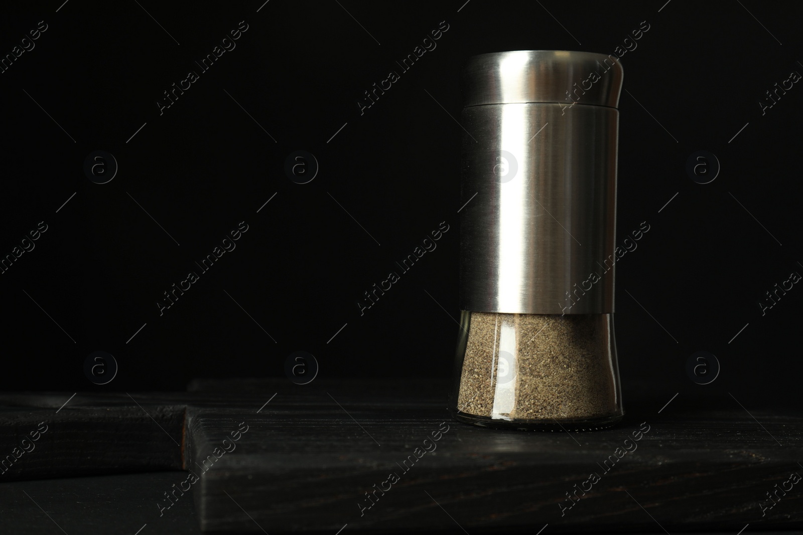 Photo of Pepper shaker on black table. Space for text