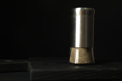 Photo of Pepper shaker on black table. Space for text