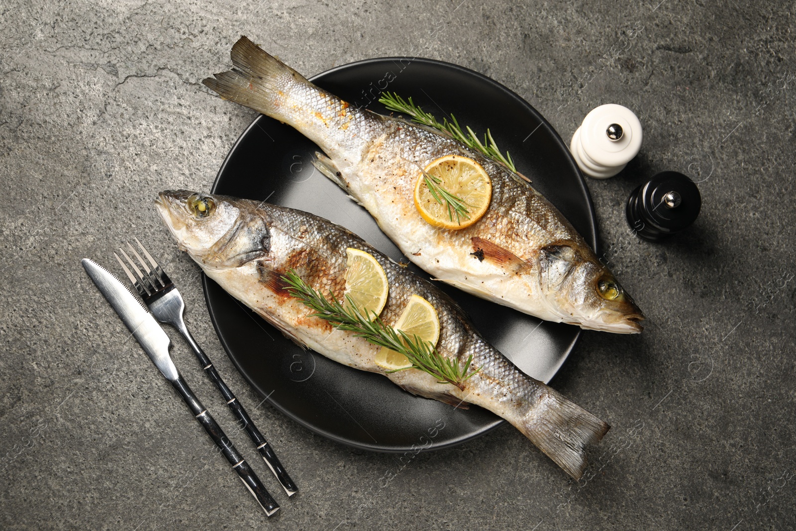 Photo of Delicious baked fish served on grey table, flat lay