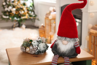 Cute Christmas gnome on wooden table in room with festive decorations