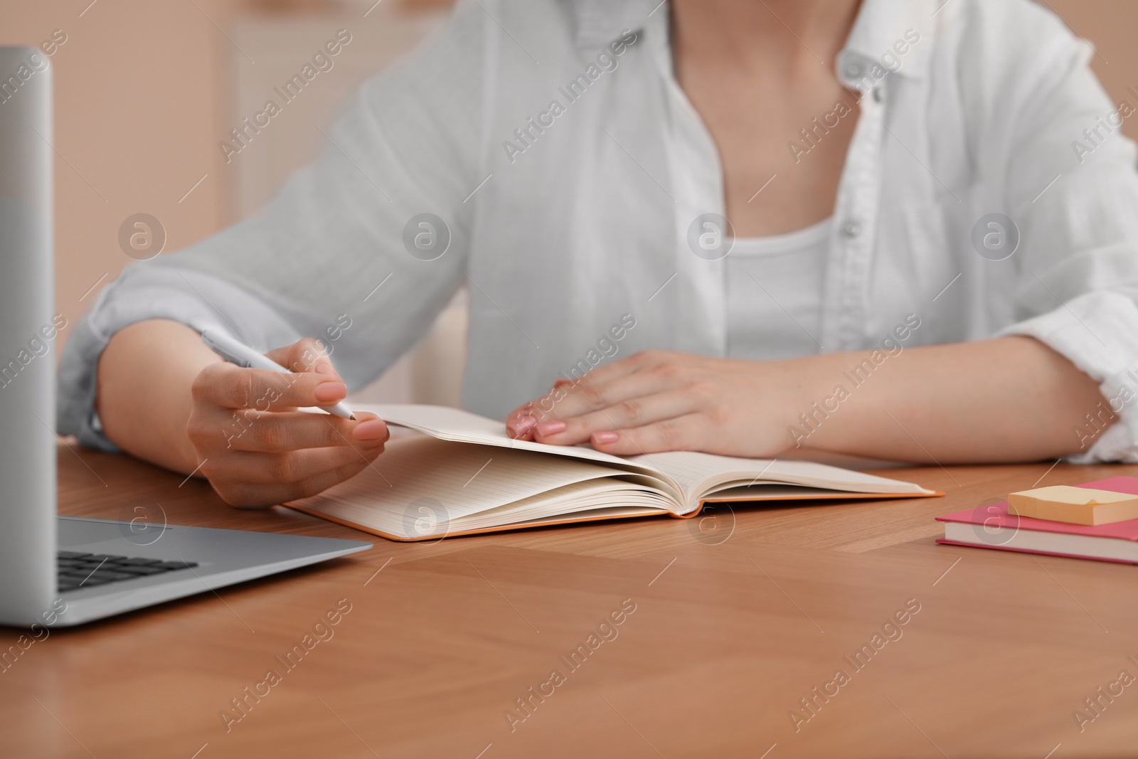 Photo of Woman with notebook at wooden table indoors, closeup