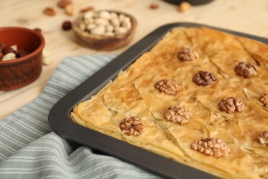 Photo of Delicious baklava with walnuts in baking pan on table, closeup