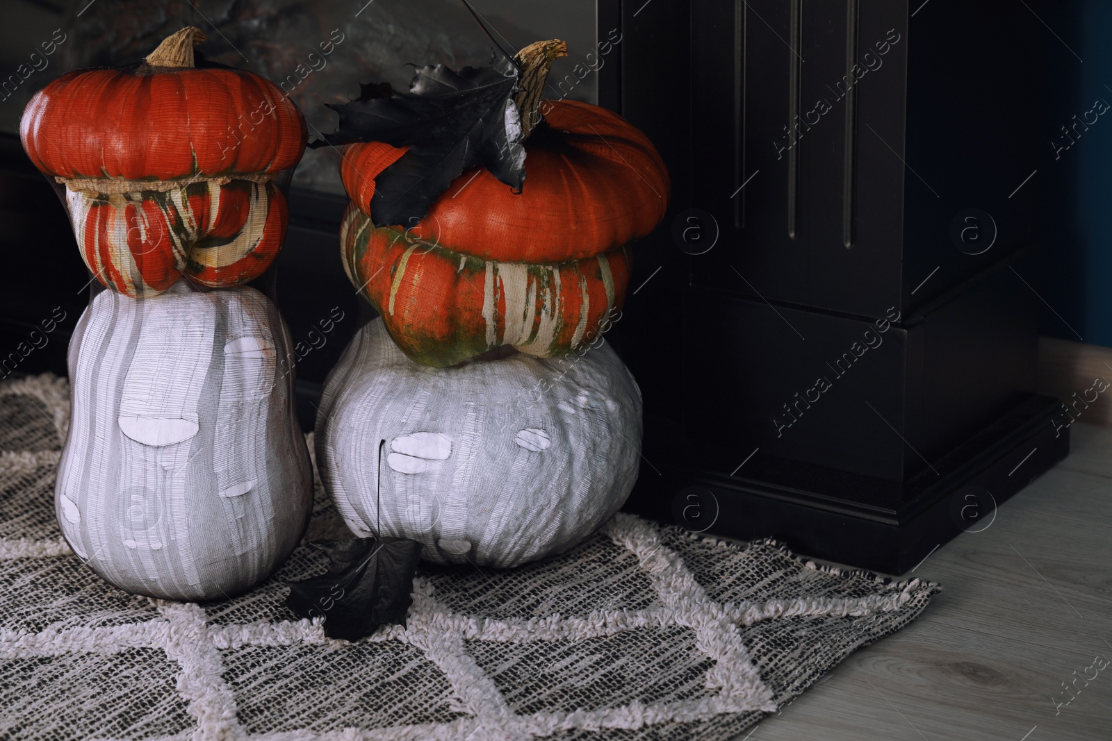 Photo of Colorful pumpkins on rug near fireplace. Halloween decorations