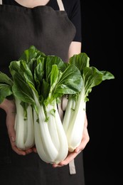 Woman holding bok choy cabbage on black background, closeup