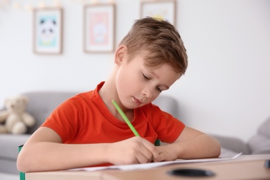 Photo of Little boy with autistic disorder drawing at home