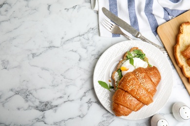 Delicious croissant with arugula and egg on white marble table, flat lay. Space for text