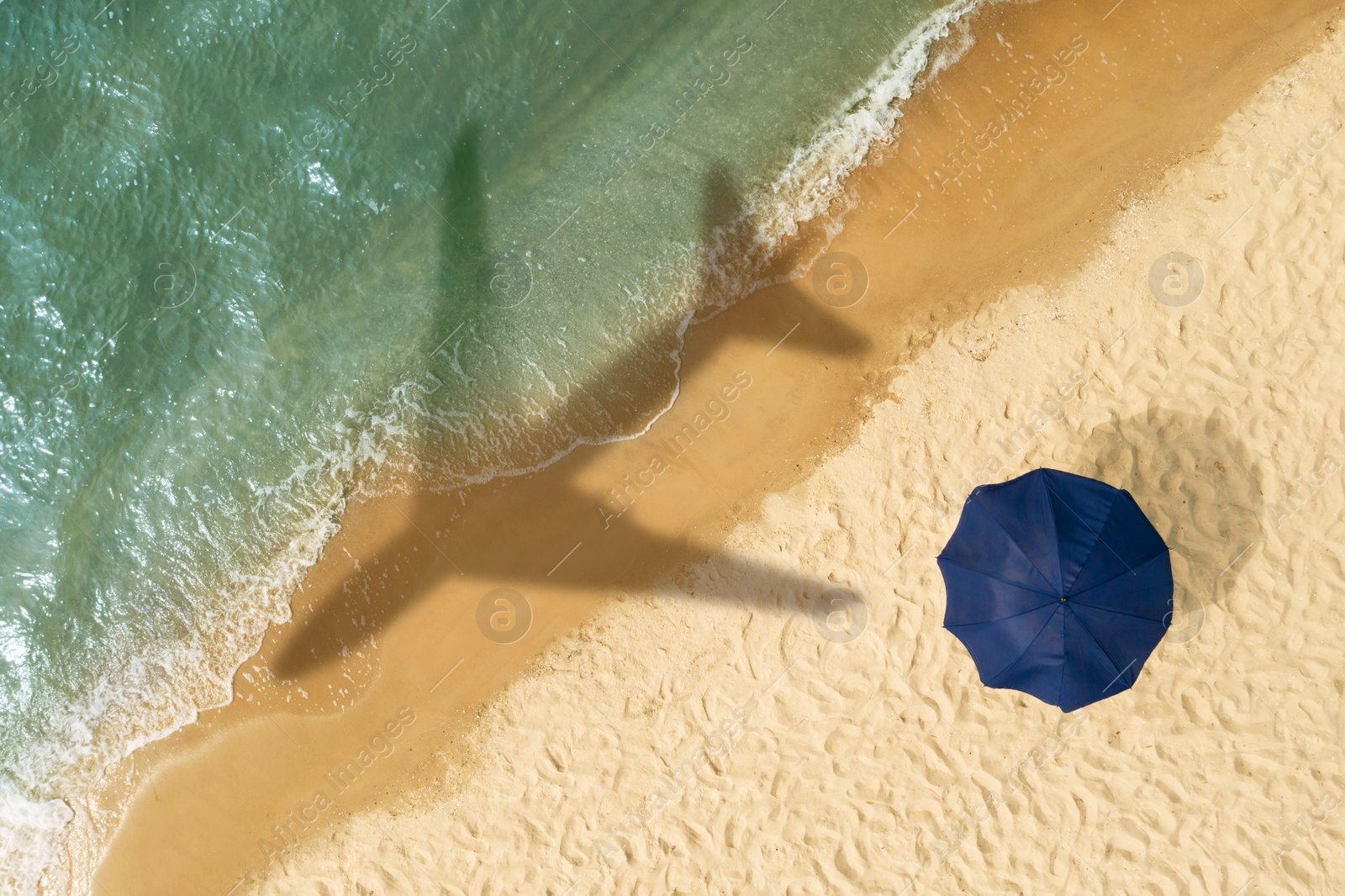 Image of Shadow of airplane above sandy coast, aerial view. Summer vacation