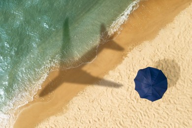 Shadow of airplane above sandy coast, aerial view. Summer vacation