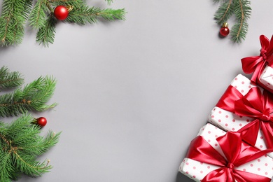 Flat lay composition with gift boxes and fir branches on grey background, top view