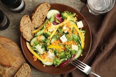 Photo of Delicious salad with lentils, vegetables and bread served on wooden table, flat lay