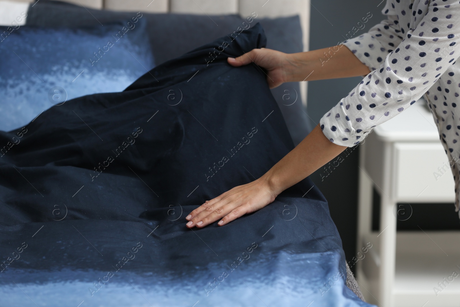 Photo of Woman making bed at home, closeup of hands
