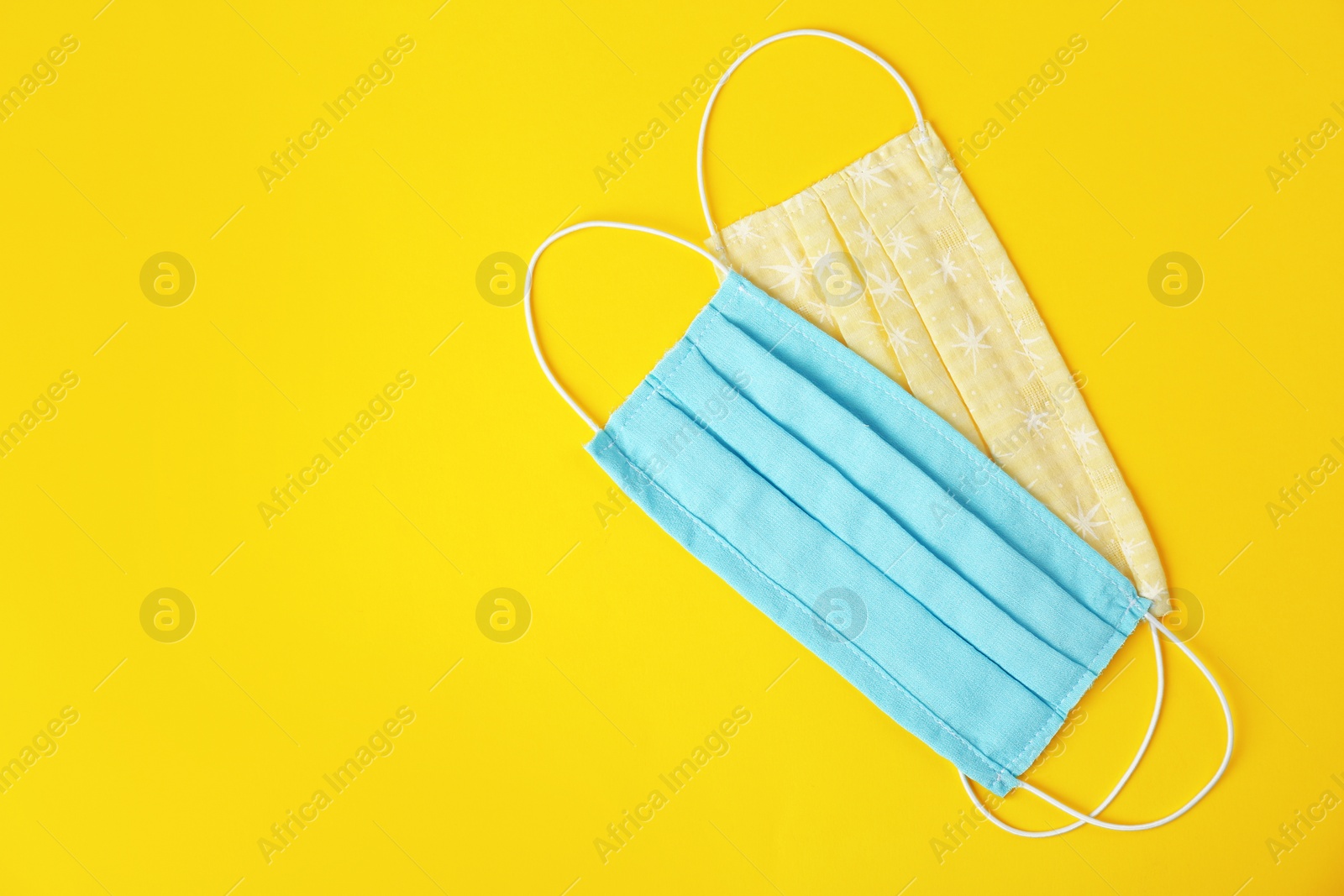 Photo of Homemade protective face masks on yellow background, flat lay. Space for text