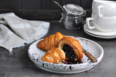 Tasty fresh croissants with jam on grey table