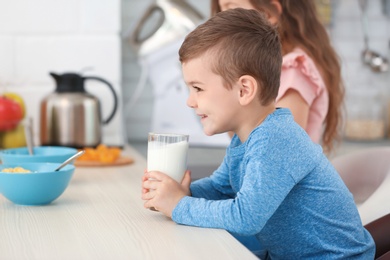 Photo of Cute little boy drinking milk in kitchen
