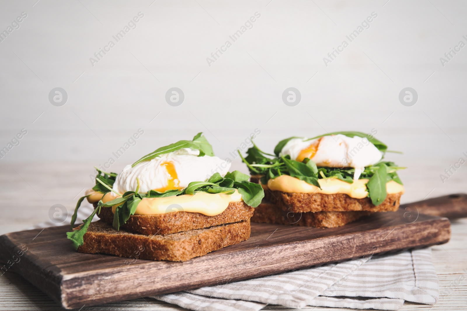 Photo of Delicious sandwiches with arugula and egg on white wooden table