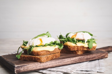 Photo of Delicious sandwiches with arugula and egg on white wooden table