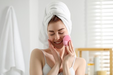 Photo of Washing face. Young woman with cleansing brush indoors