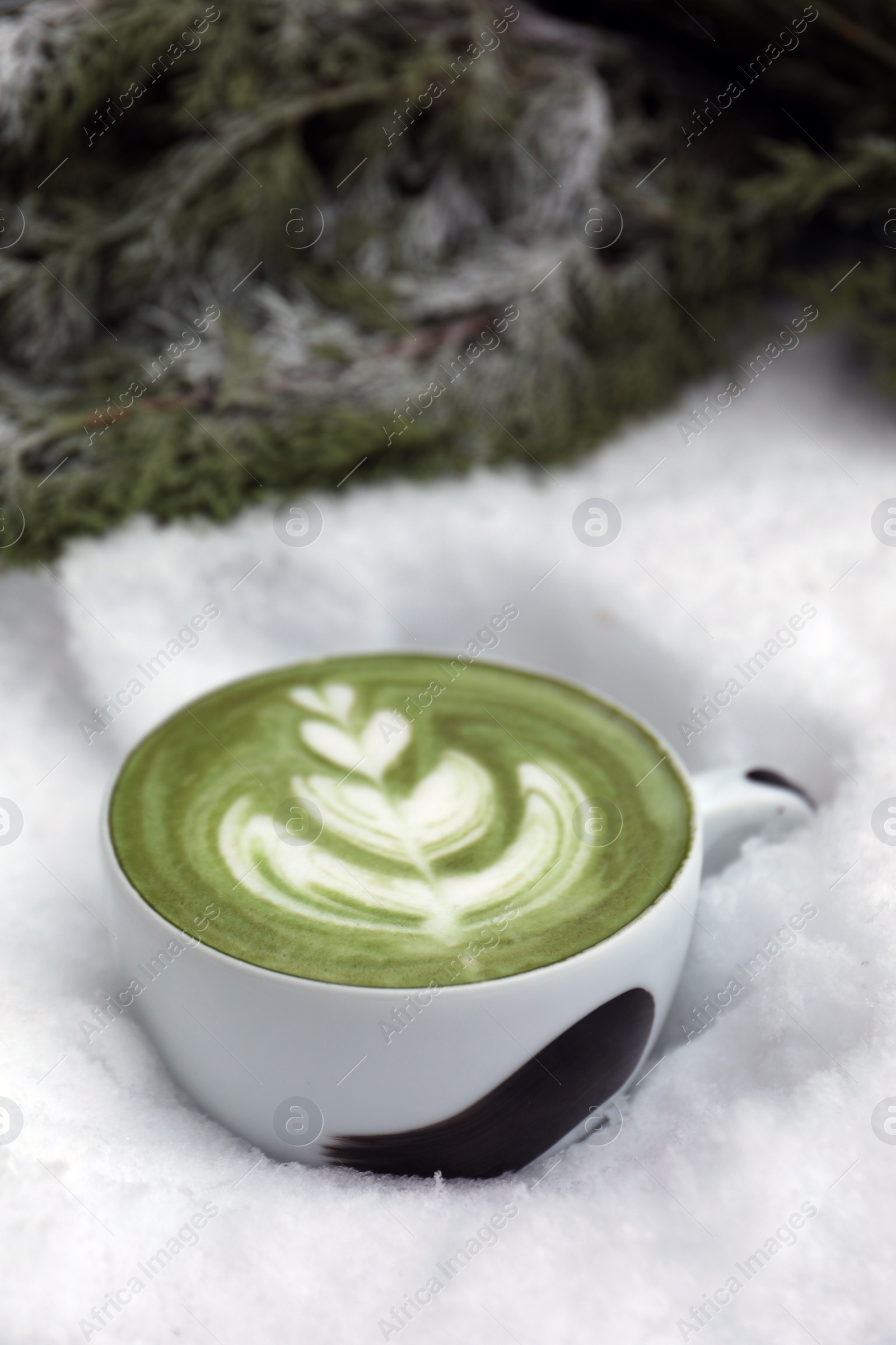 Photo of Cup of fresh matcha latte in snow outdoors
