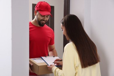 Photo of Woman signing for delivered parcel at home