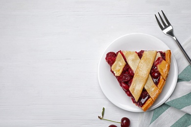 Photo of Slice of delicious fresh cherry pie served on white wooden table, flat lay. Space for text