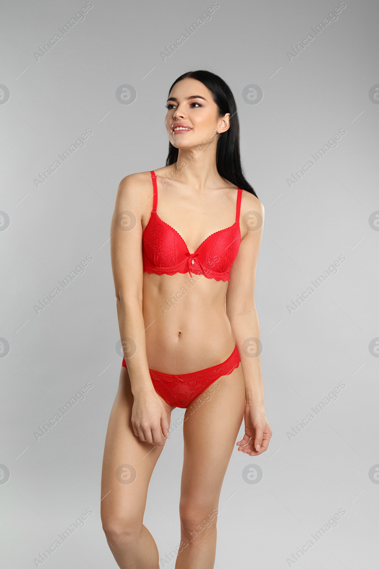 Photo of Beautiful young woman in red underwear on grey background