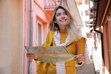 Tourist with map walking on city street