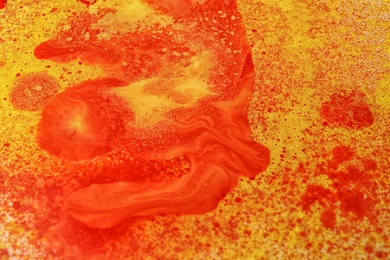 Texture of orange paint with colorful splotches as background, closeup