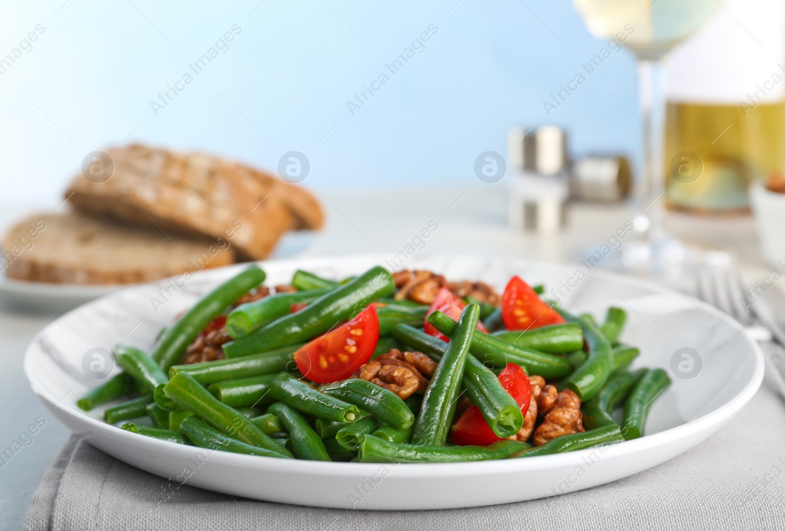 Photo of Tasty green beans with walnuts and tomatoes served for dinner on table