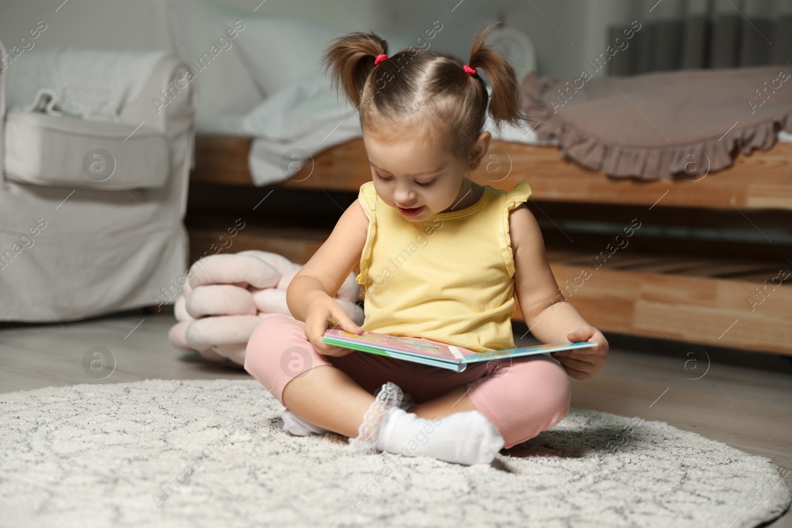 Photo of Cute little girl with book at home