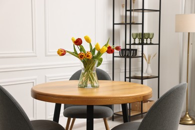 Stylish dining room interior with comfortable furniture and beautiful tulips