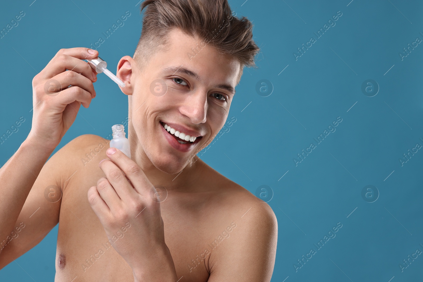 Photo of Handsome man applying serum onto his face on blue background. Space for text