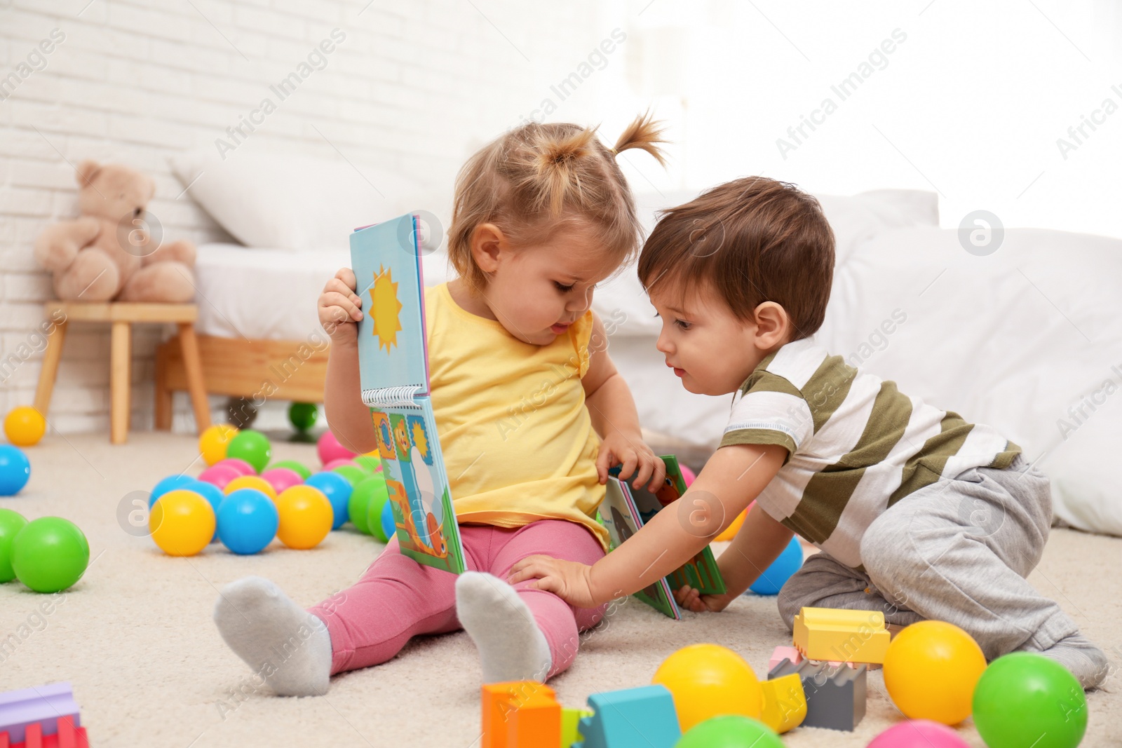 Photo of Cute little children playing with toys on floor at home