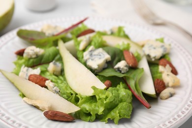 Delicious pear salad with almond and lettuce on plate, closeup