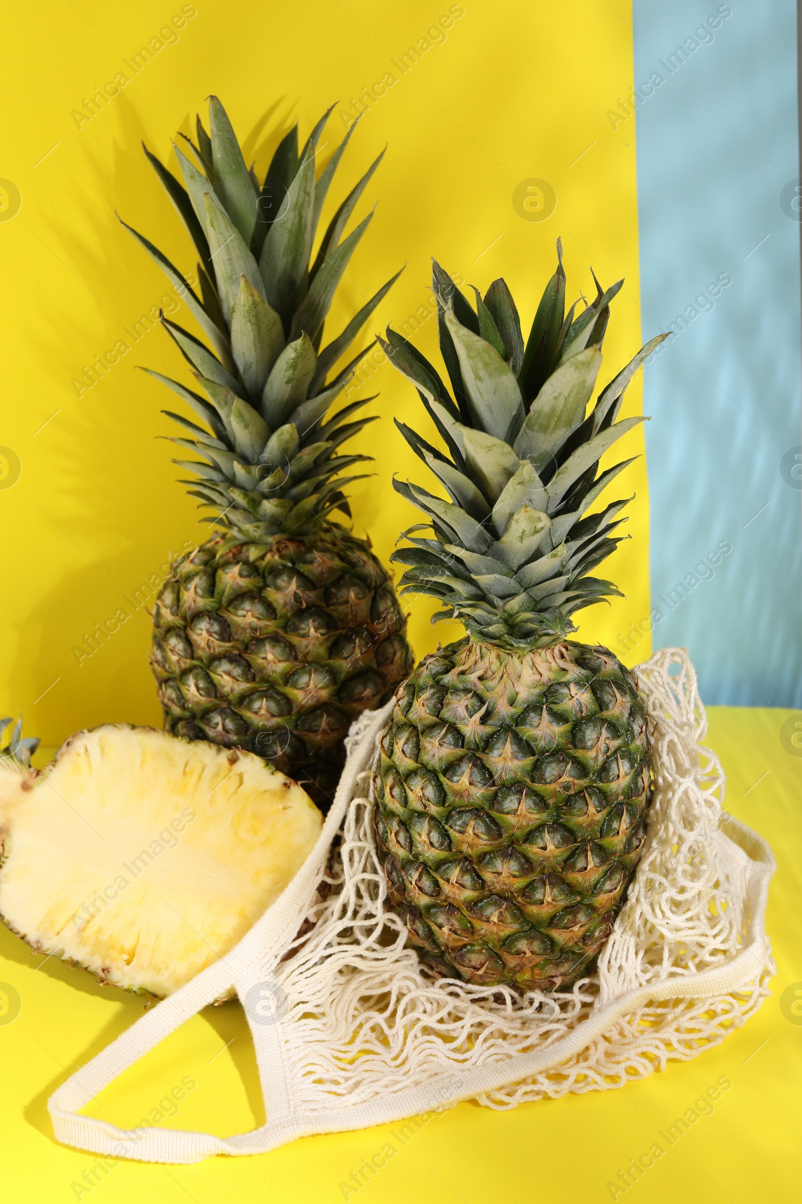 Photo of Whole and cut ripe pineapples on yellow background