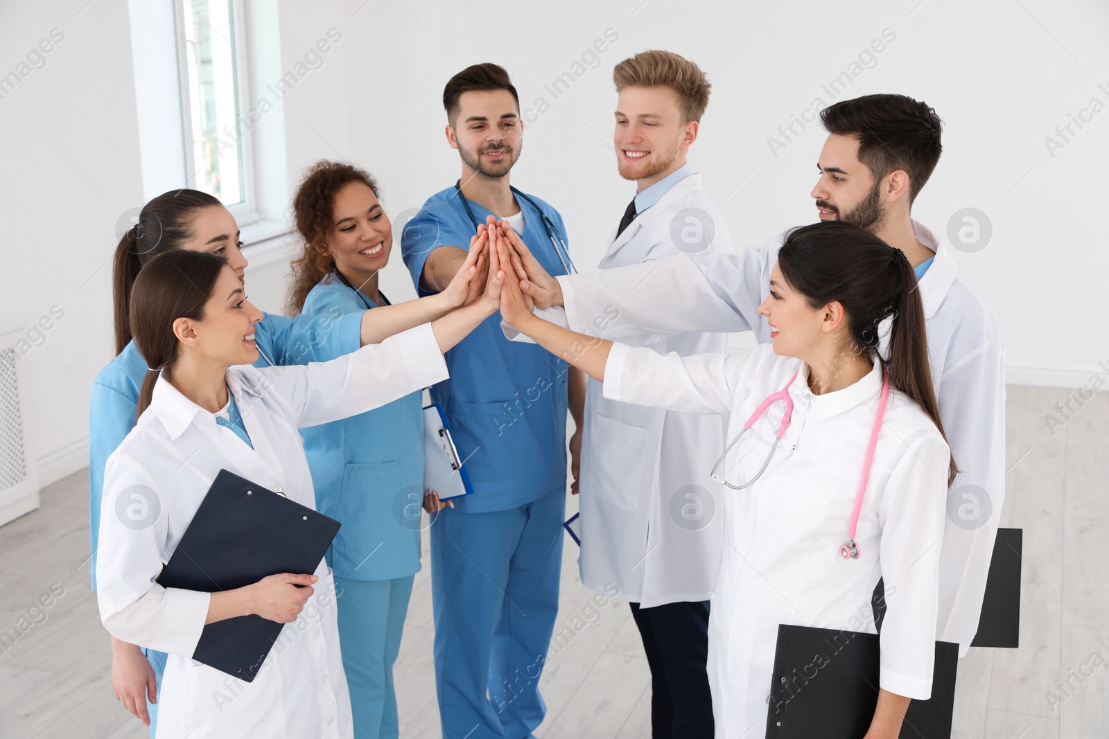 Photo of Team of medical workers holding hands together in hospital. Unity concept
