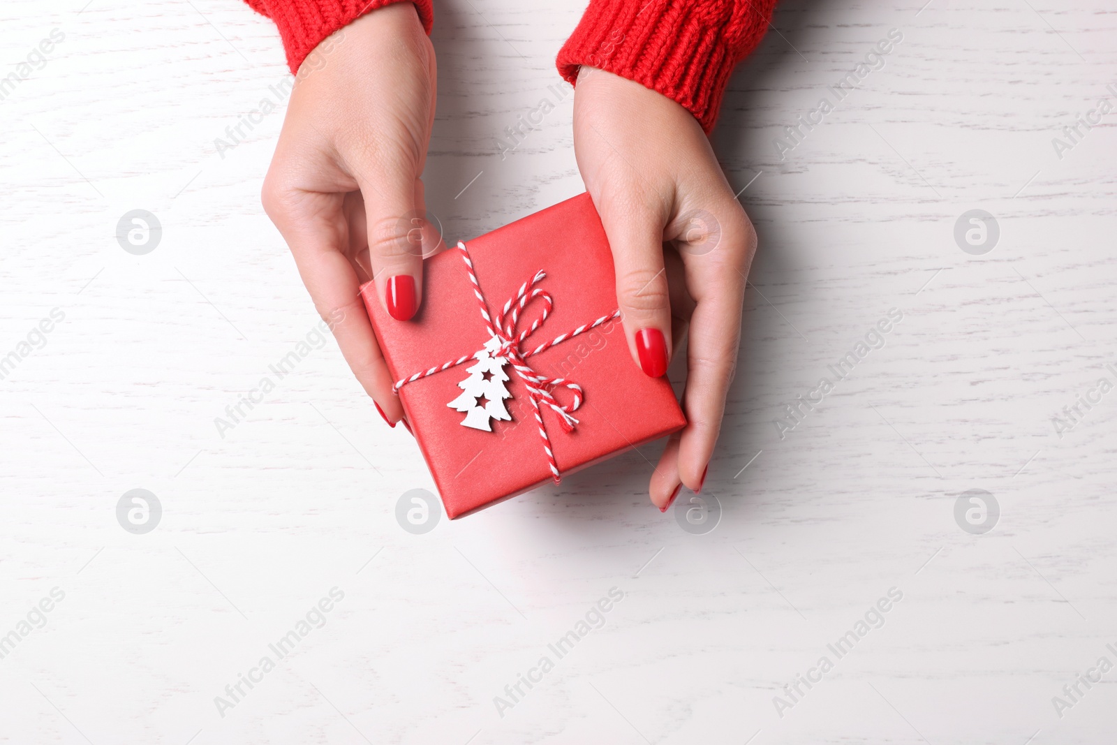 Photo of Christmas present. Woman with gift box at white wooden table, top view