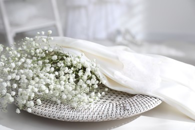 Beautiful engagement ring, wedding dress and flowers on table indoors, closeup