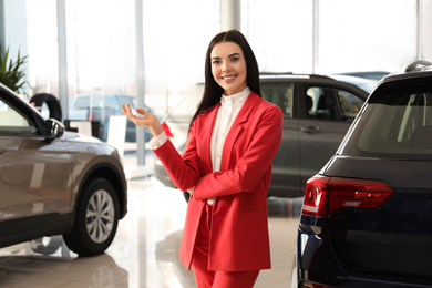 Happy young saleswoman in modern car salon